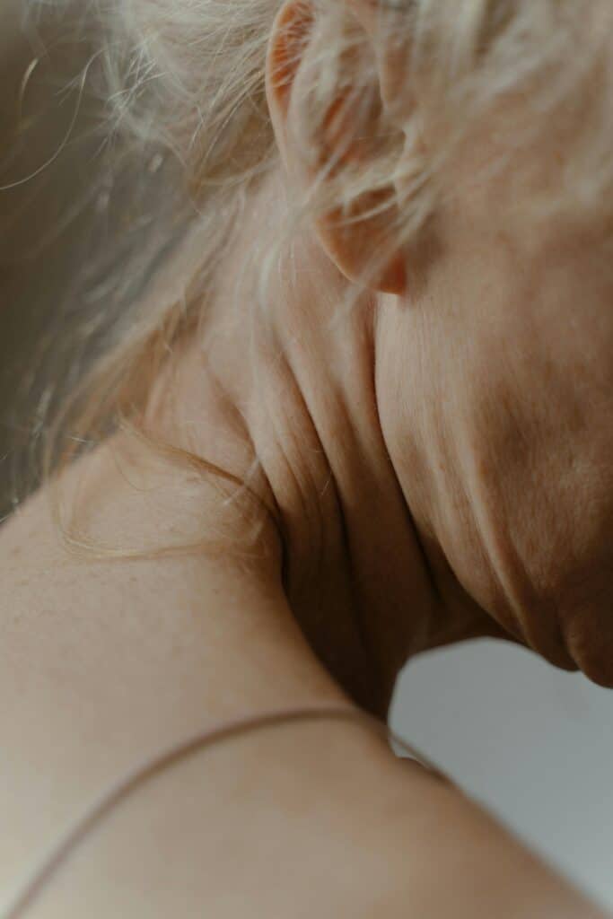Detailed view of an elderly woman's neck, showcasing aging skin and natural wrinkling.