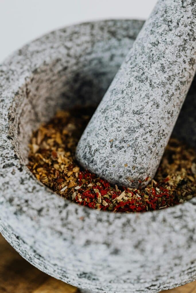 Texture-rich spices being ground in a granite mortar and pestle - perfect for culinary enthusiasts.